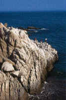 Granite cliffs, covered by white guano contrast with the blue waters of the Bayovar river.